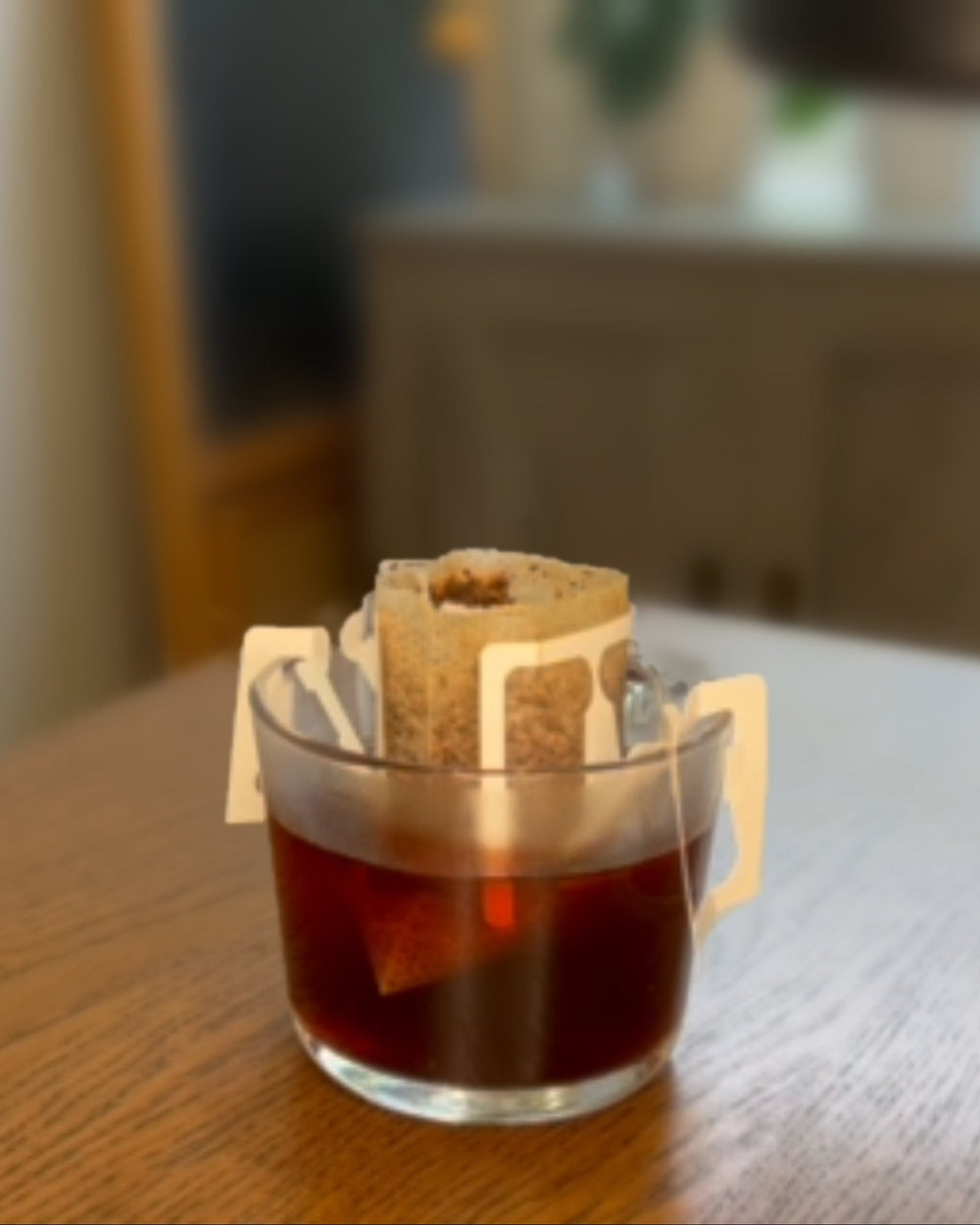 A drip bag hanging on a glass cup of coffee